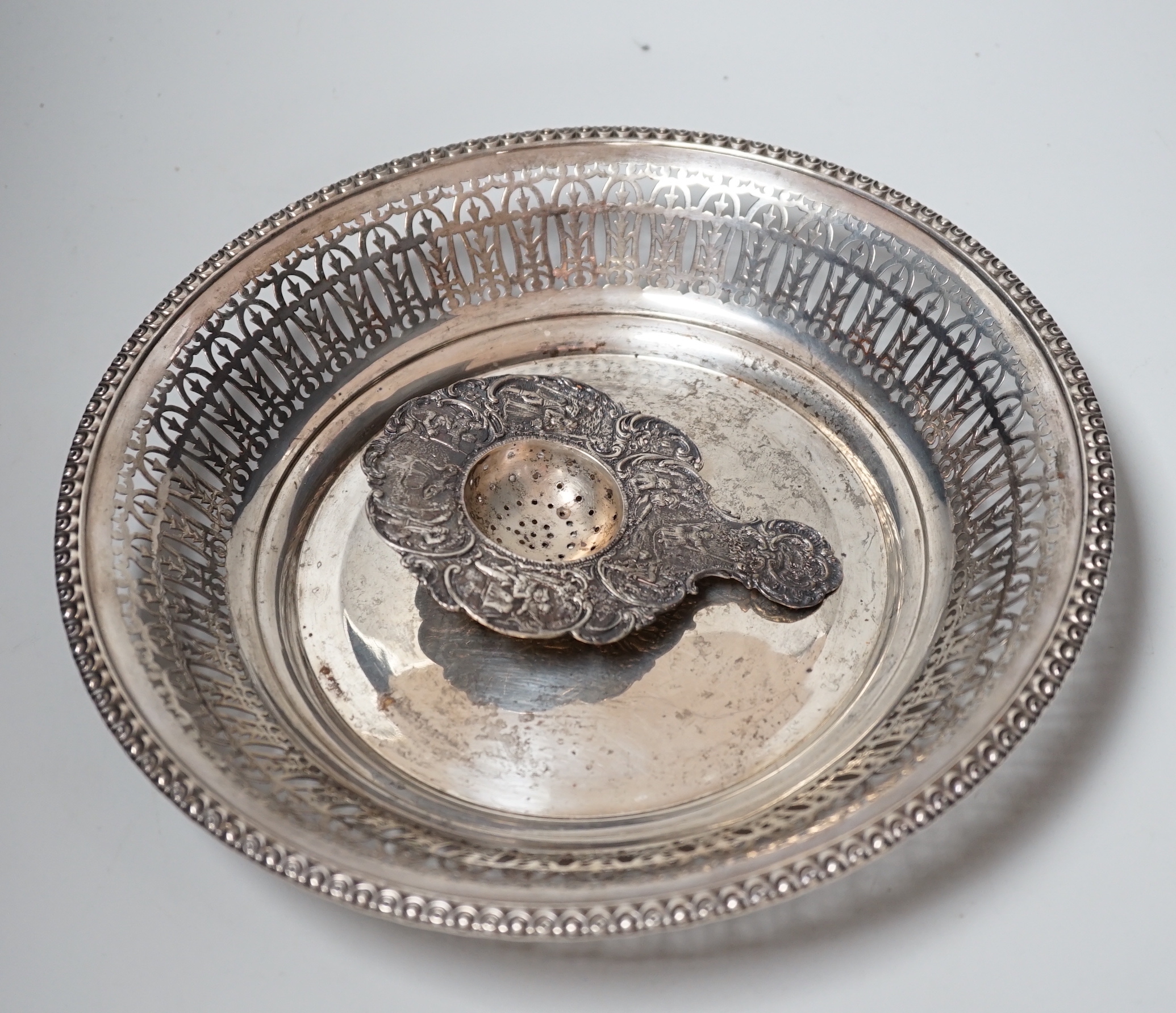 A late Victorian silver tea strainer, import marks for London, 1900 and a pierced silver plated bowl.
